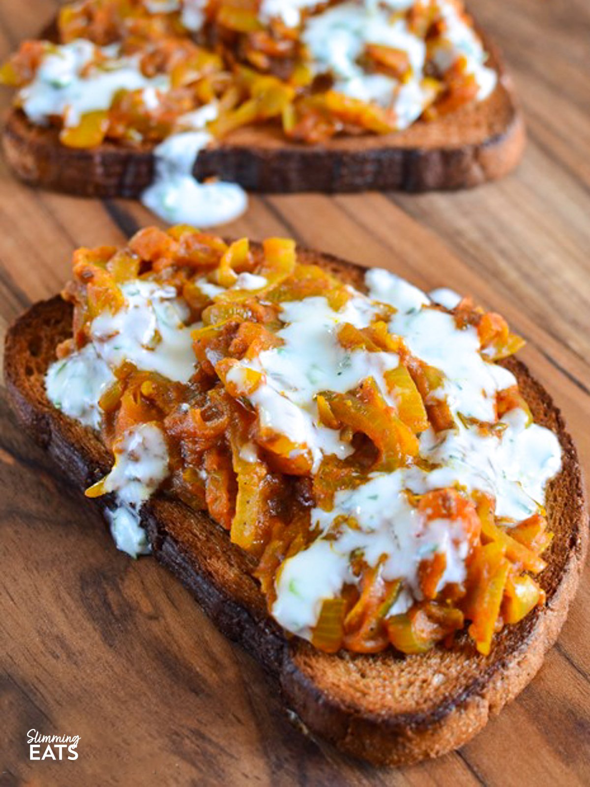 Onion Masala Toast on a wooden board drizzled with mint yoghurt