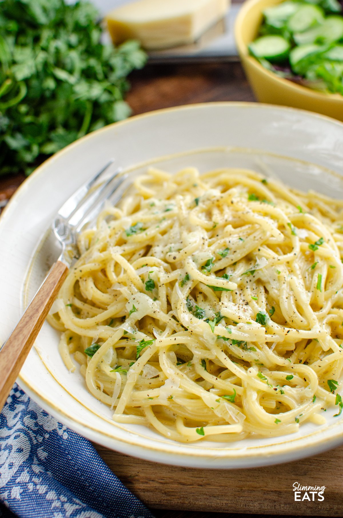 Tuck into a bowl of this irresistibly creamy garlic pasta — a quick, fuss-free one-pot dish that’s perfect for busy evenings. Made with simple, everyday ingredients and ready in under 20 minutes, it’s the kind of comforting meal the whole family will happily dive into. Creamy Garlic Pasta in a white bowl with yellow rim, fork place in bowl on left hand side with blue patterned napkin