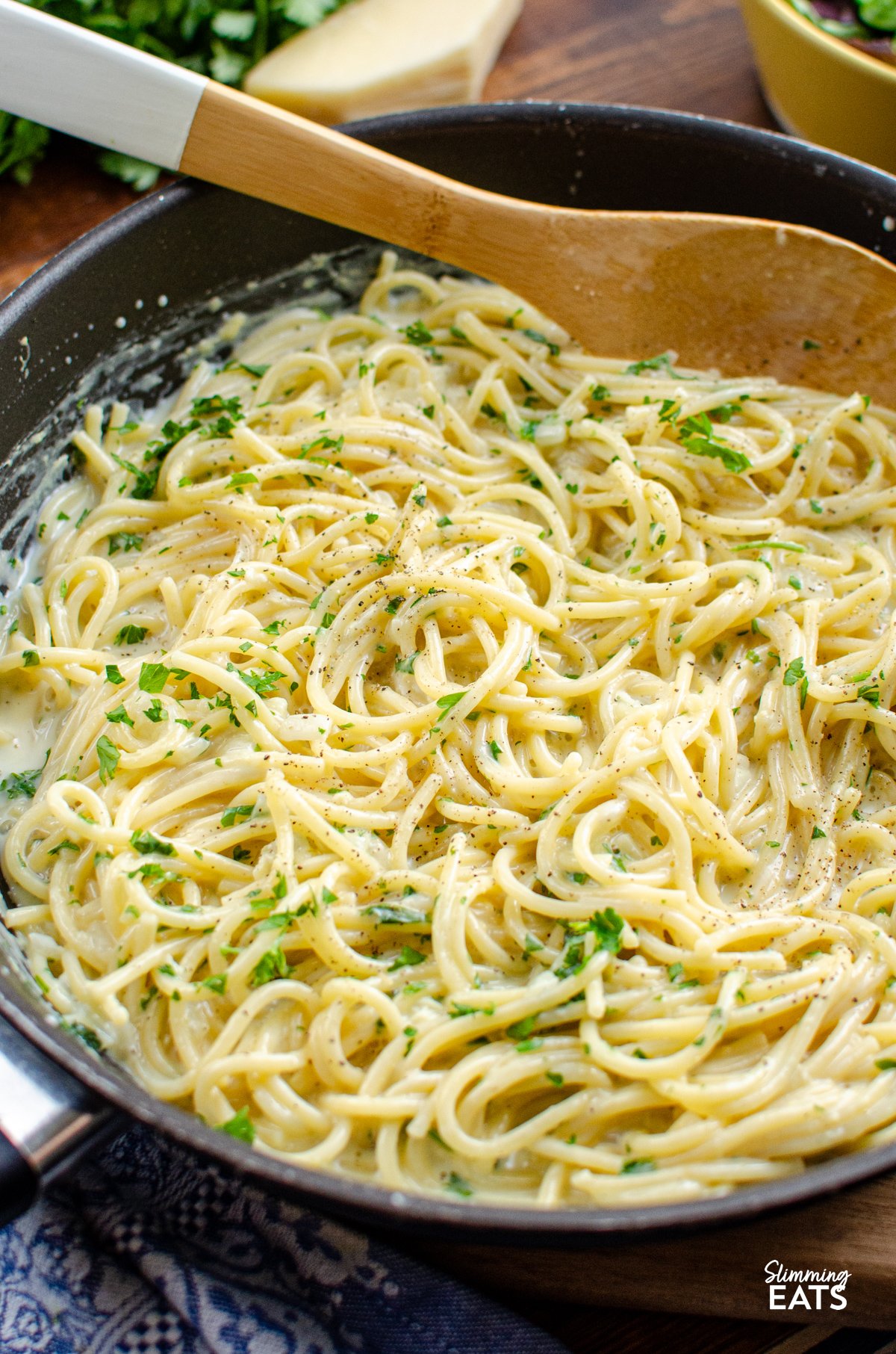 Tuck into a bowl of this irresistibly creamy garlic pasta — a quick, fuss-free one-pot dish that’s perfect for busy evenings. Made with simple, everyday ingredients and ready in under 20 minutes, it’s the kind of comforting meal the whole family will happily dive into. Creamy Garlic Pasta in a deep frying pan with wooden spoon, surrounded by components of the recipe