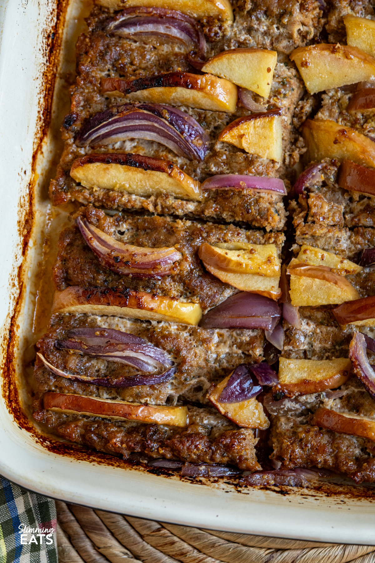 close up of apple and red onion pork apple squares baked and sliced up in oven dish