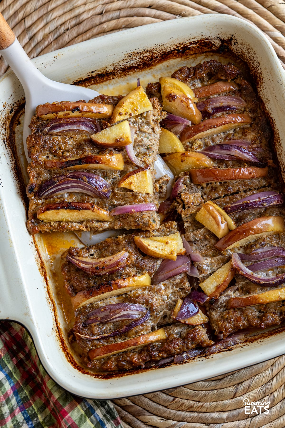 apple and red onion pork apple squares baked and sliced up in oven dish with spatula