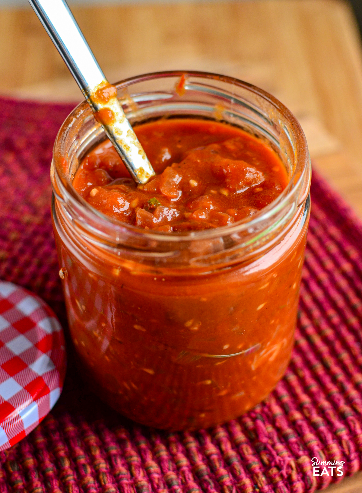 tomato red onion relish in a glass jar with a spoon