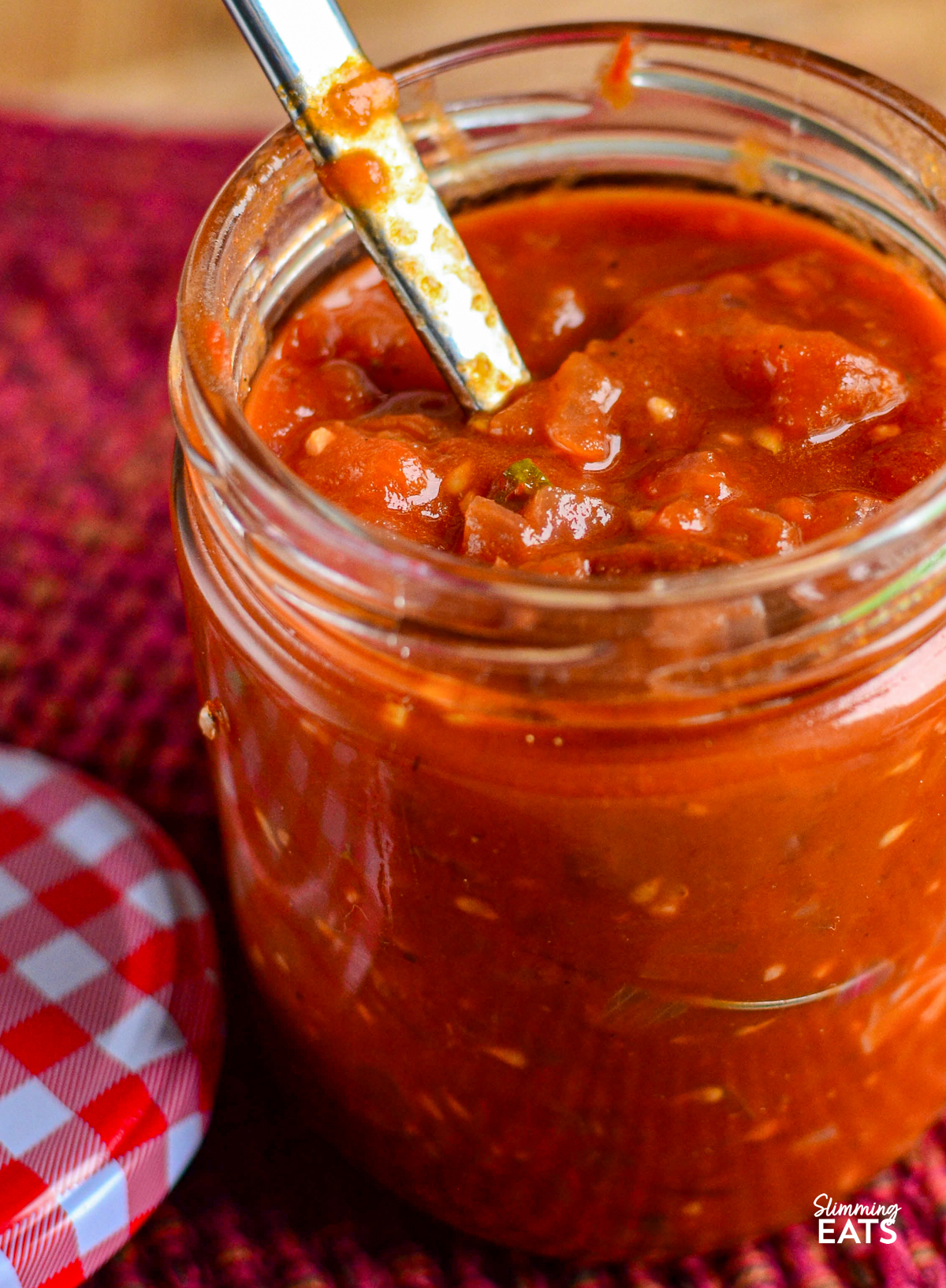 tomato red onion relish in a glass jar with a spoon