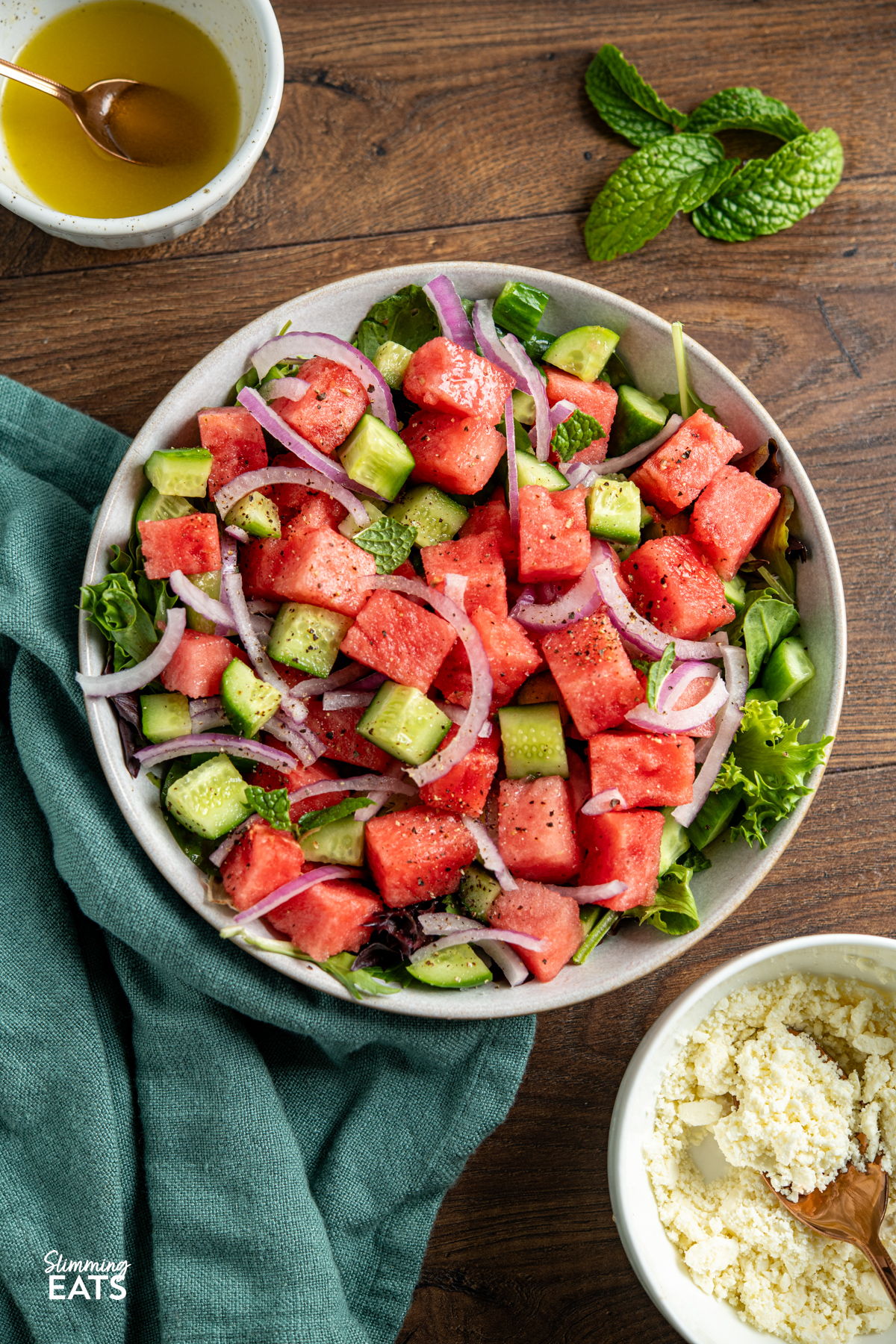 Watermelon feta salad is the perfect fresh and vibrant side for warm days, with juicy watermelon, crisp cucumber, salty feta and a light dressing bringing it all together beautifully. Watermelon and Feta Salad in a bowl surrounded by fresh mint and a small bowl with the dressing