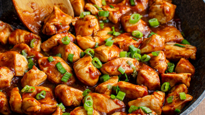hoisin chicken in a grey non stick frying pan with wooden spoon