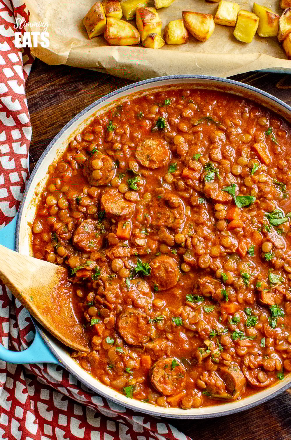 One Pot Sausage and Lentil Casserole - super easy recipe that the whole family will enjoy | gluten free, dairy free, Slimming Eats and Weight Watchers friendly One Pot Sausage and Lentil Casserole in enamelled cast iron skillet with Wooden spoon and roast potato on baking tray