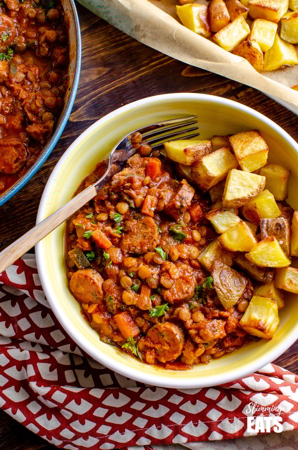One Pot Sausage and Lentil Casserole - super easy recipe that the whole family will enjoy | gluten free, dairy free, Slimming Eats and Weight Watchers friendly over top view of One Pot Sausage and Lentil Casserole in white and yellow bowl with roast potatoes and wooden handled fork