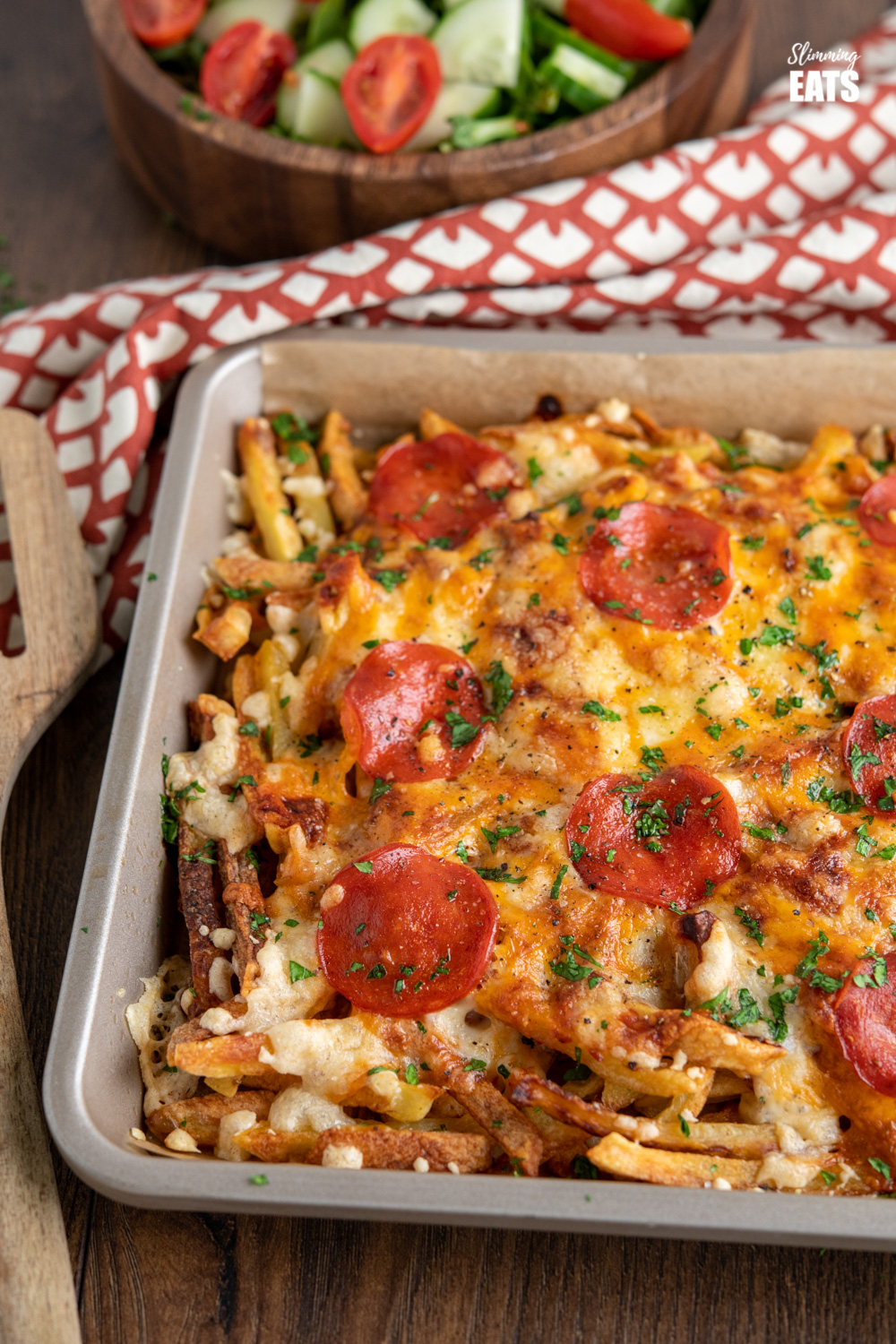 baking tray with Cheesy Oven Baked Pizza Fries and bowl of salad