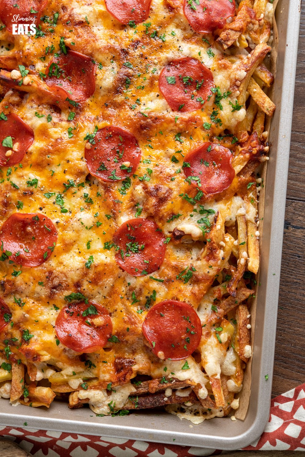 Cheesy Oven Baked Pizza Fries (from www.slimmingeats.com) - the ultimate sharing traybake for all the pizza lovers out there. Homemade oven-baked fries, delicious pizza sauce and yummy melted cheesy goodness. #pizza #fries #Potatoes #slimmingeats #weightwatchers #glutenfree close up of Cheesy Oven Baked Pizza Fries on baking sheet