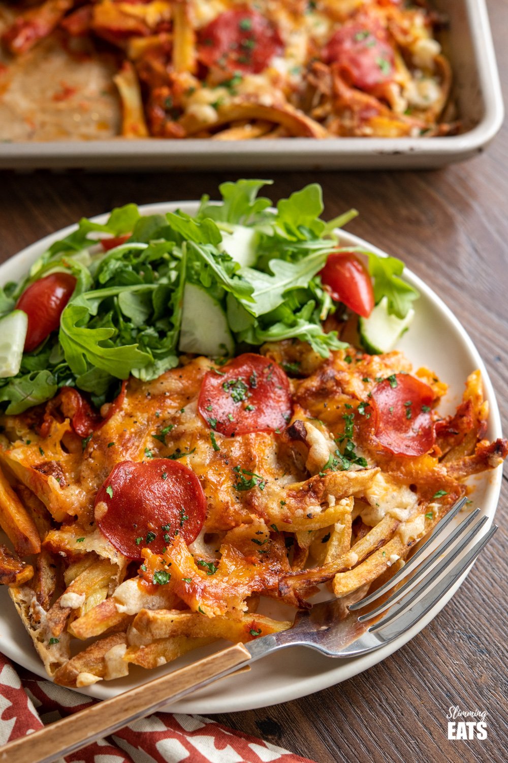 Cheesy Oven Baked Pizza Fries (from www.slimmingeats.com) - the ultimate sharing traybake for all the pizza lovers out there. Homemade oven-baked fries, delicious pizza sauce and yummy melted cheesy goodness. #pizza #fries #Potatoes #slimmingeats #weightwatchers #glutenfree Cheesy Oven Baked Pizza Fries on cream plate with salad