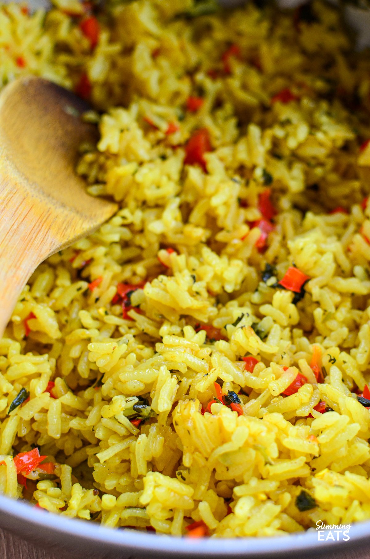 Add a burst of flavour to your meal with this Red Pepper and Coriander Rice. Soft, savoury rice is gently infused with garlic and onion, sautéed in olive oil, and simmered in vegetable stock for extra depth. The sweetness of red bell peppers finished with fresh coriander, it’s a simple, flavourful dish that’s sure to impress. red pepper coriander rice in stainless steel pan with wooden spoon