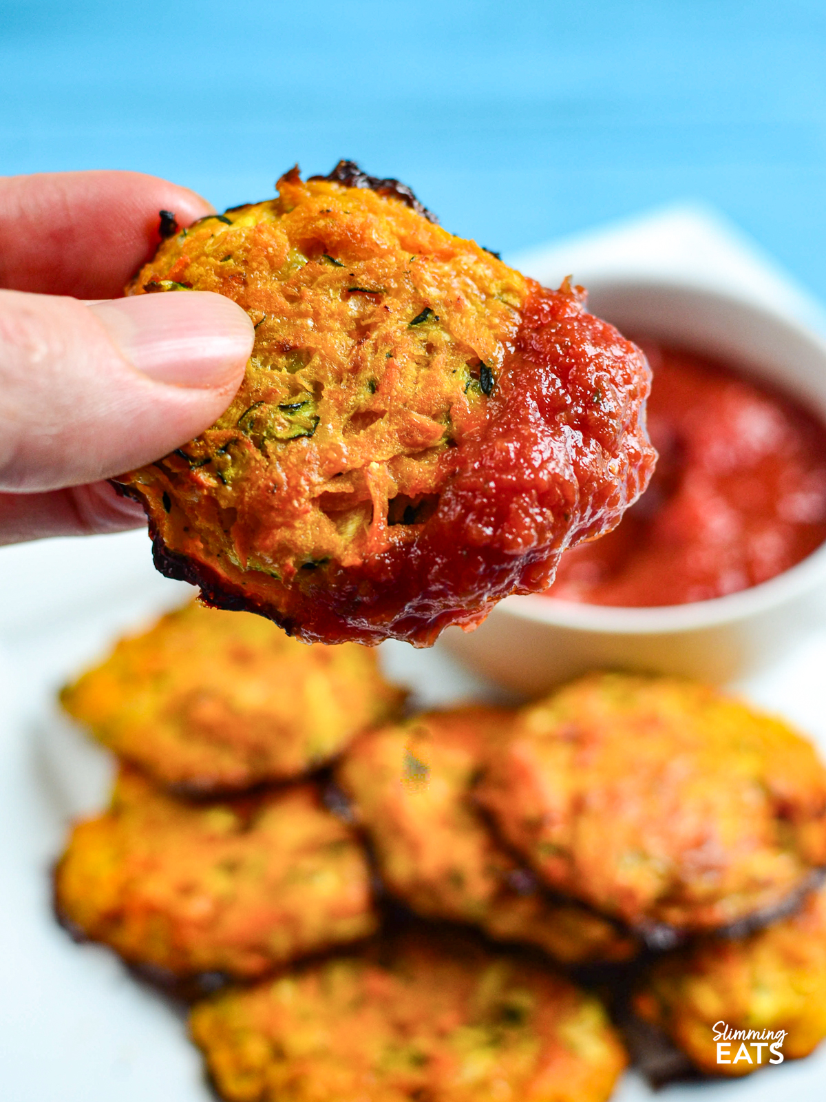 Cheesy Sweet Potato and Zucchini Bites dipped into a bowl of pizza sauce