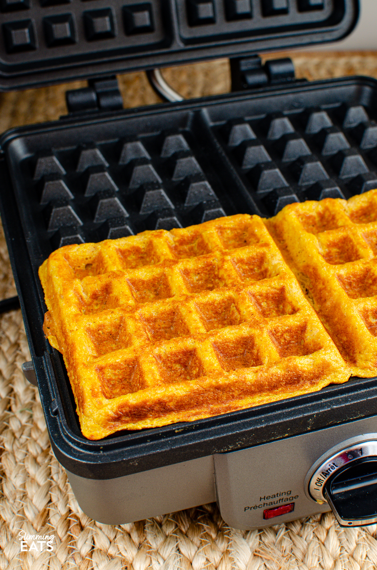 Perfectly cooked pumpkin waffles resting in a square waffle iron, showcasing their golden-brown exterior, ready to be served and enjoyed.