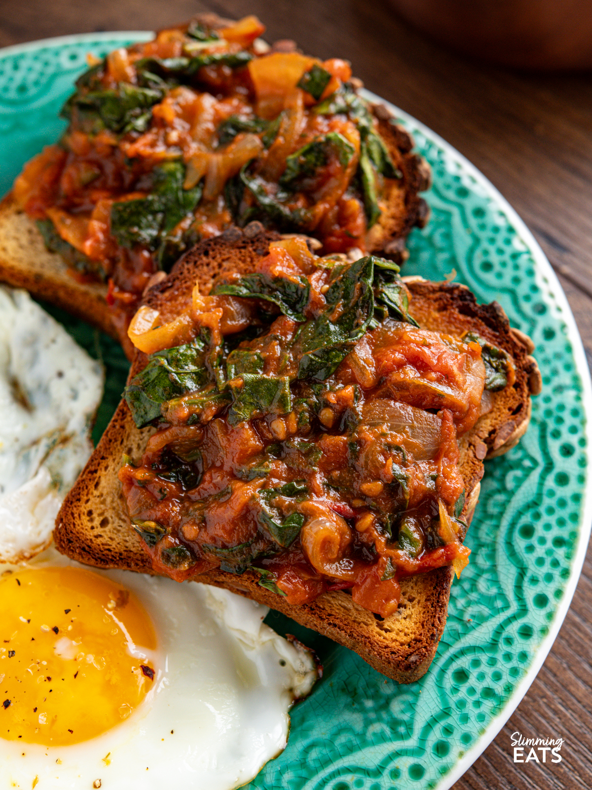 balsamic tomatoes and spinach on toast with eggs on a turquoise plate