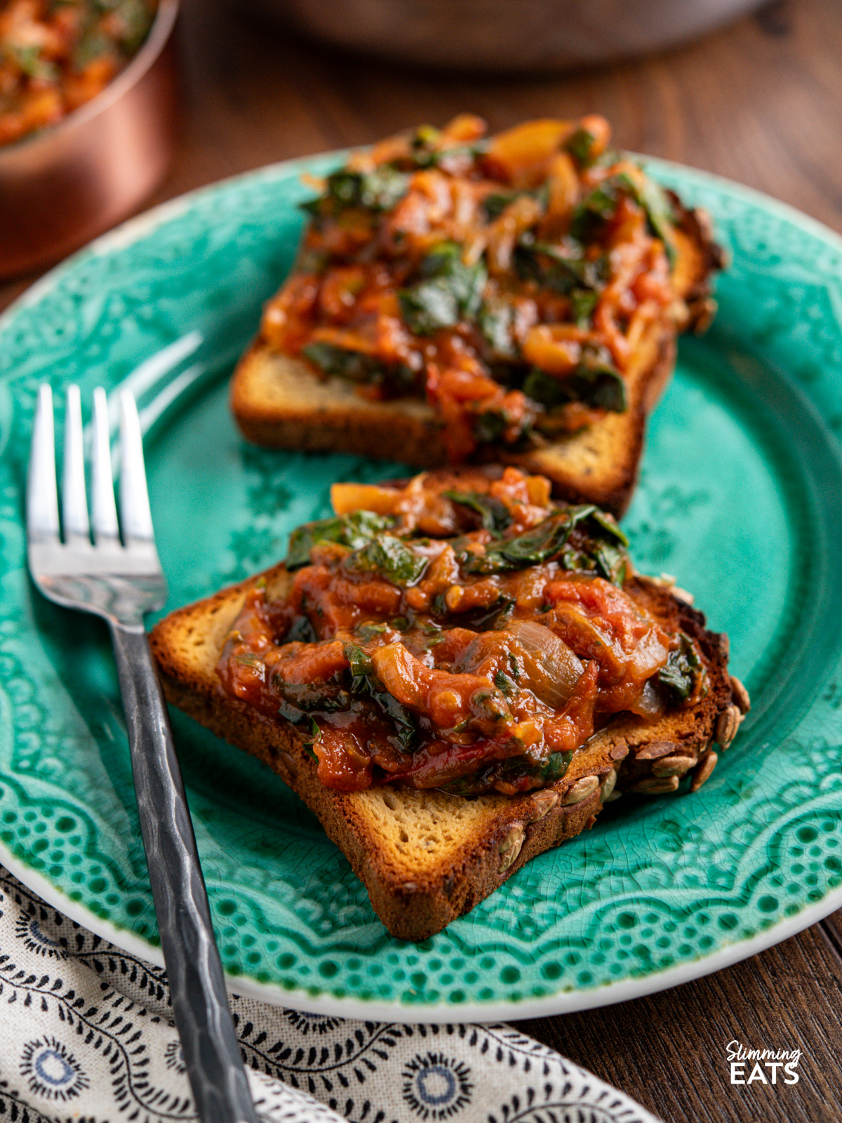balsamic tomatoes and spinach on toast with eggs on a turquoise plate
