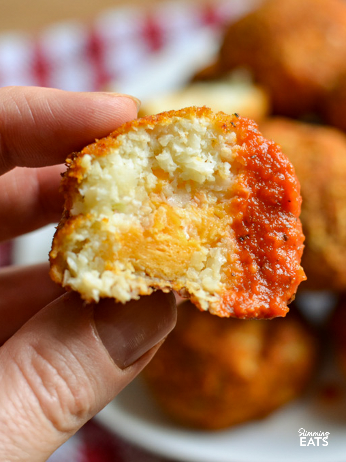 cheddar stuffed cauliflower bites in half showing cheddar after being dipped in tomato basil dip
