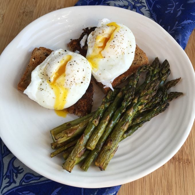 Cheats Poached Eggs on whole wheat toast with asparagus on a white plate