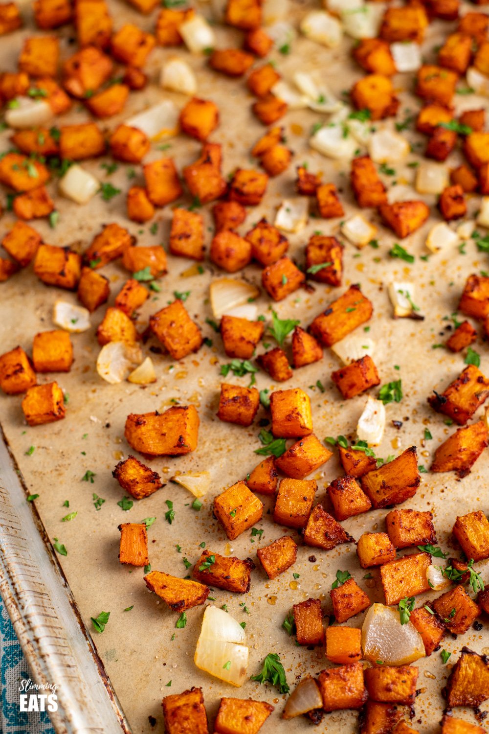 close up of seasoned roasted butternut squash on baking tray lined with parchment