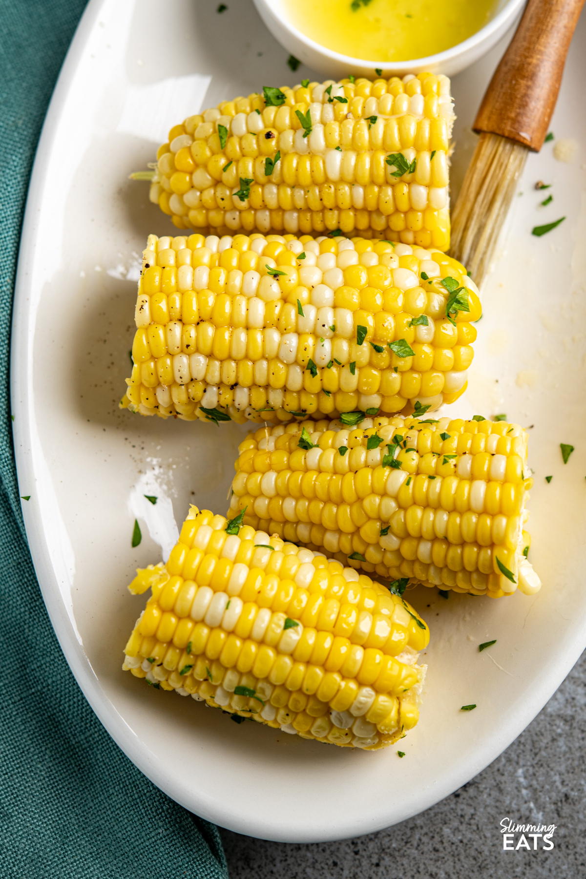 CORN ON THE COB ON A OVAL PLATE WITH MELTED BUTTER IN A DISH