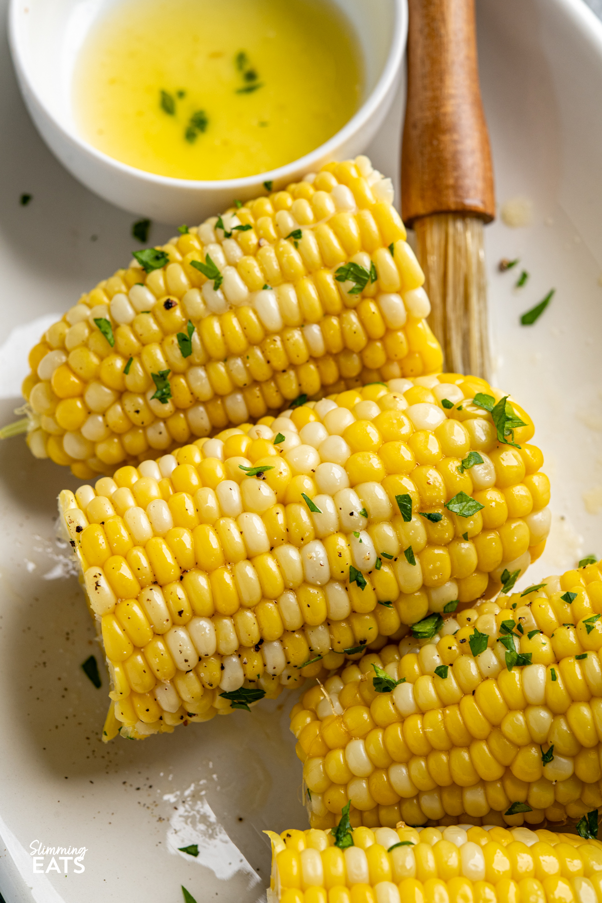 CORN ON THE COB ON A OVAL PLATE WITH MELTED BUTTER IN A DISH