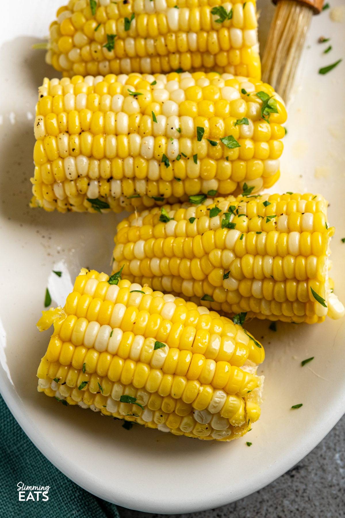 CORN ON THE COB ON A OVAL PLATE WITH MELTED BUTTER IN A DISH