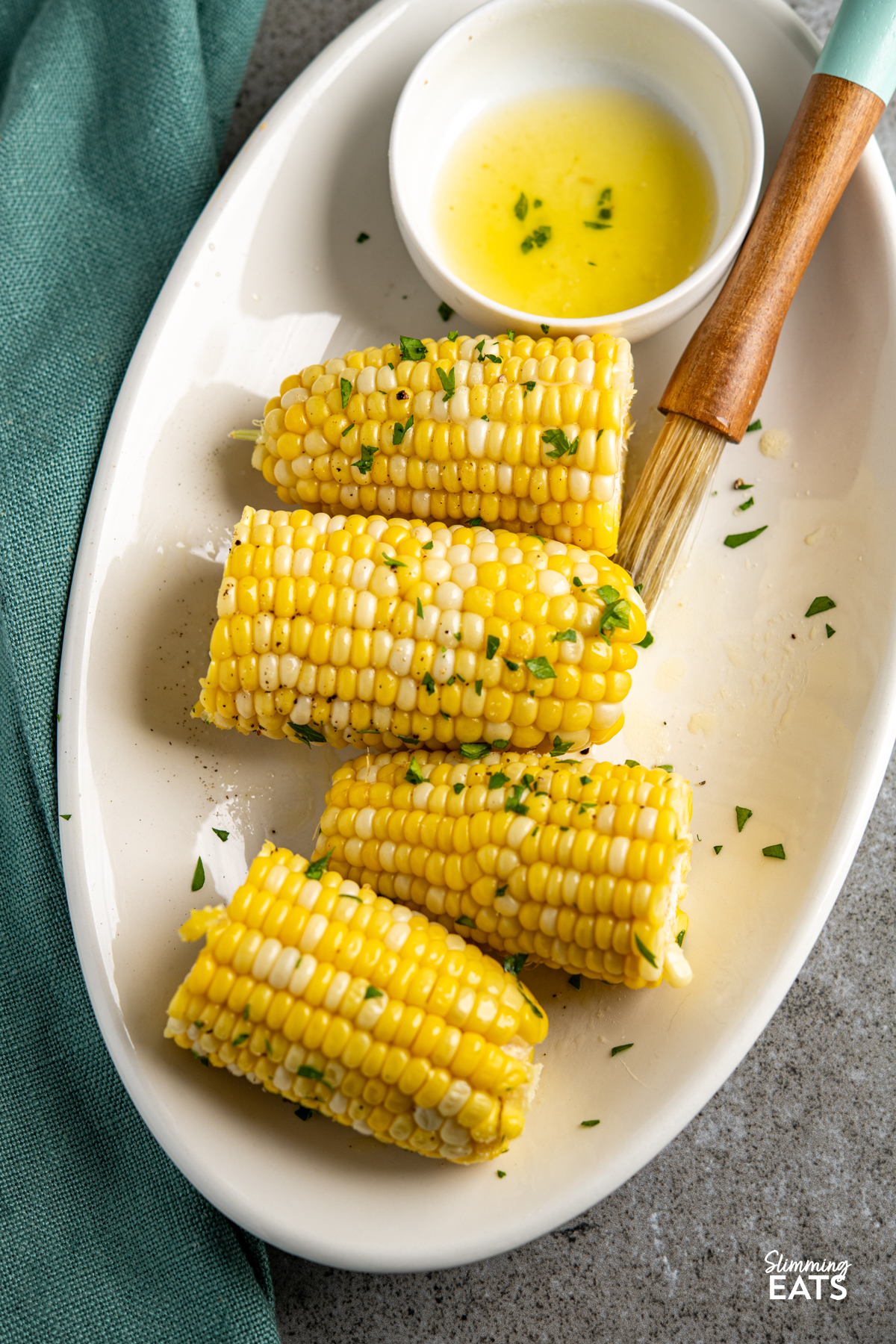 CORN ON THE COB ON A OVAL PLATE WITH MELTED BUTTER IN A DISH