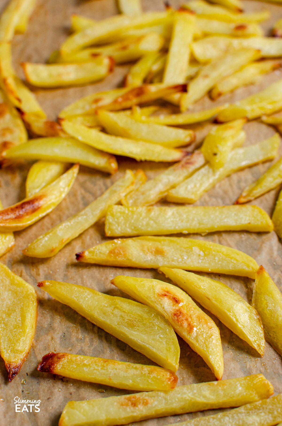 close up of Homemade Oven Baked Chip Shop Style Chips on parchment paper