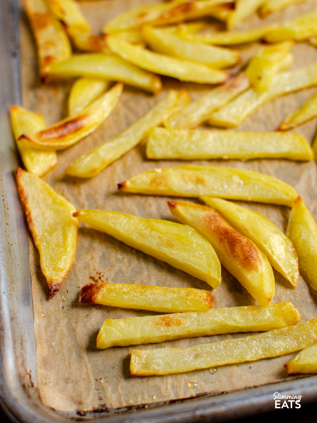 close up of Homemade Oven Baked Chip Shop Style Chips on parchment paper