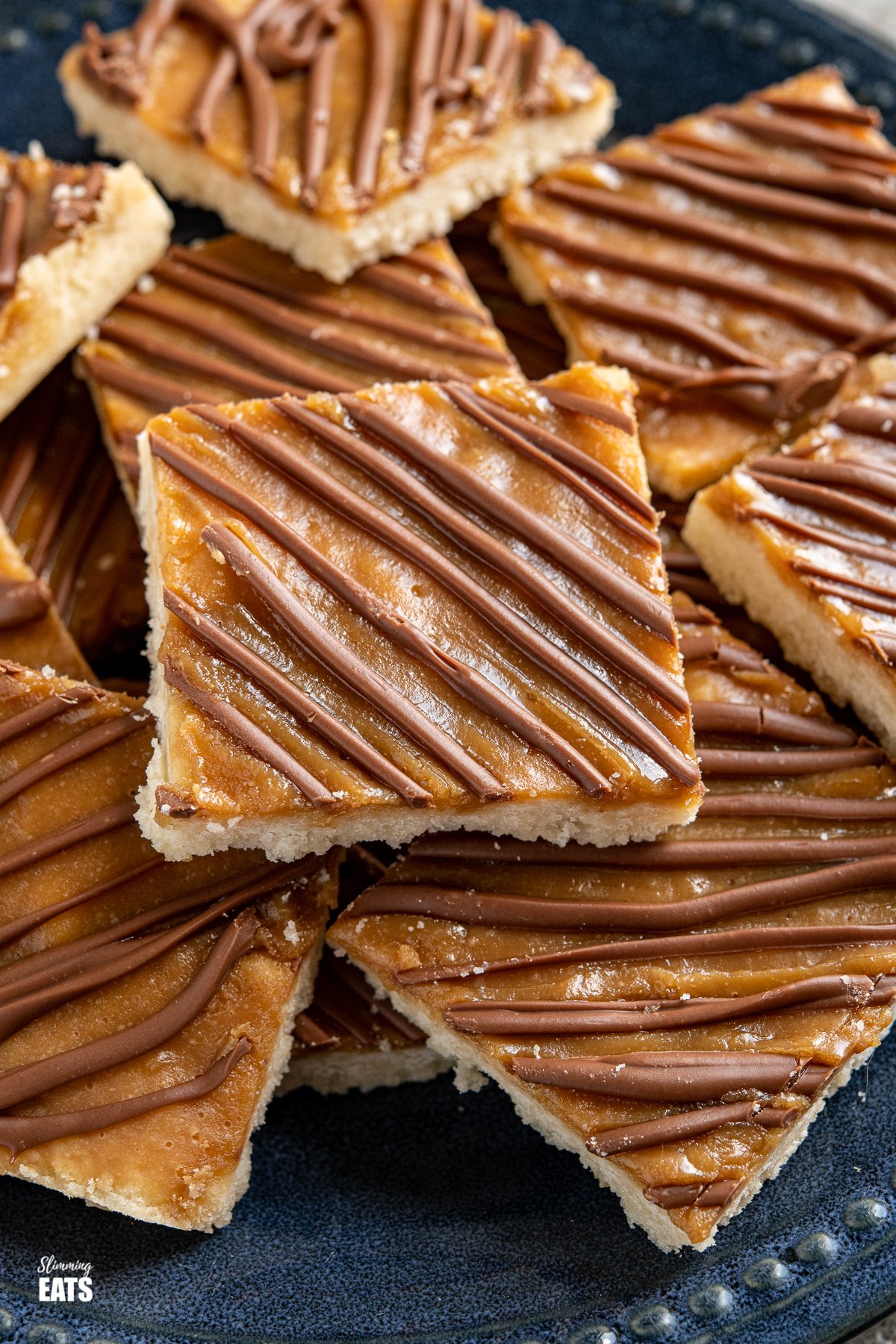 close up of Millionaires Shortbread Squares on a dark blue navy plate