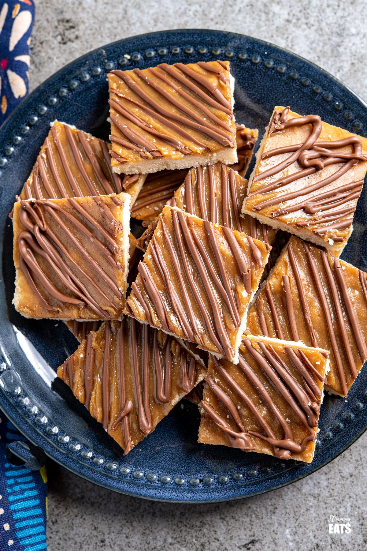 Millionaires Shortbread - these delicious Millionaires Shortbread squares have all the delicious taste of their regular version, but are lower in sugar and calories. Slimming World and Weight Watchers friendlylimming World and Weight Watchers friendly over top view of Millionaires Shortbread Squares on a dark blue navy plate