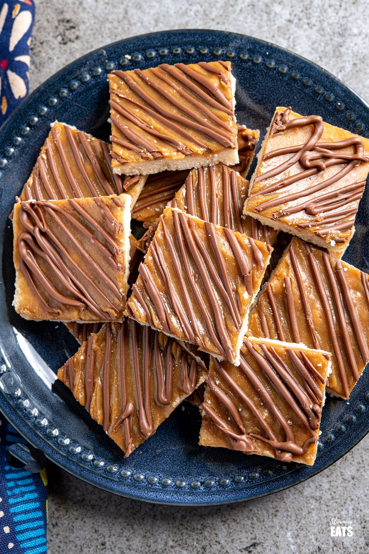 over top view of  Millionaires Shortbread Squares on a dark blue navy plate