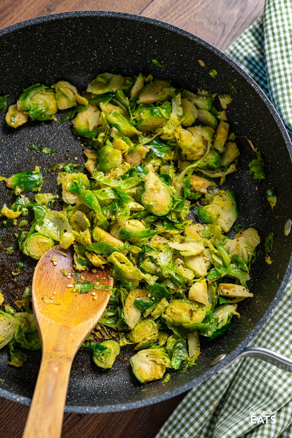 Sauteed Shredded Garlic Brussel Sprouts in non stick frying pan with wooden spoon