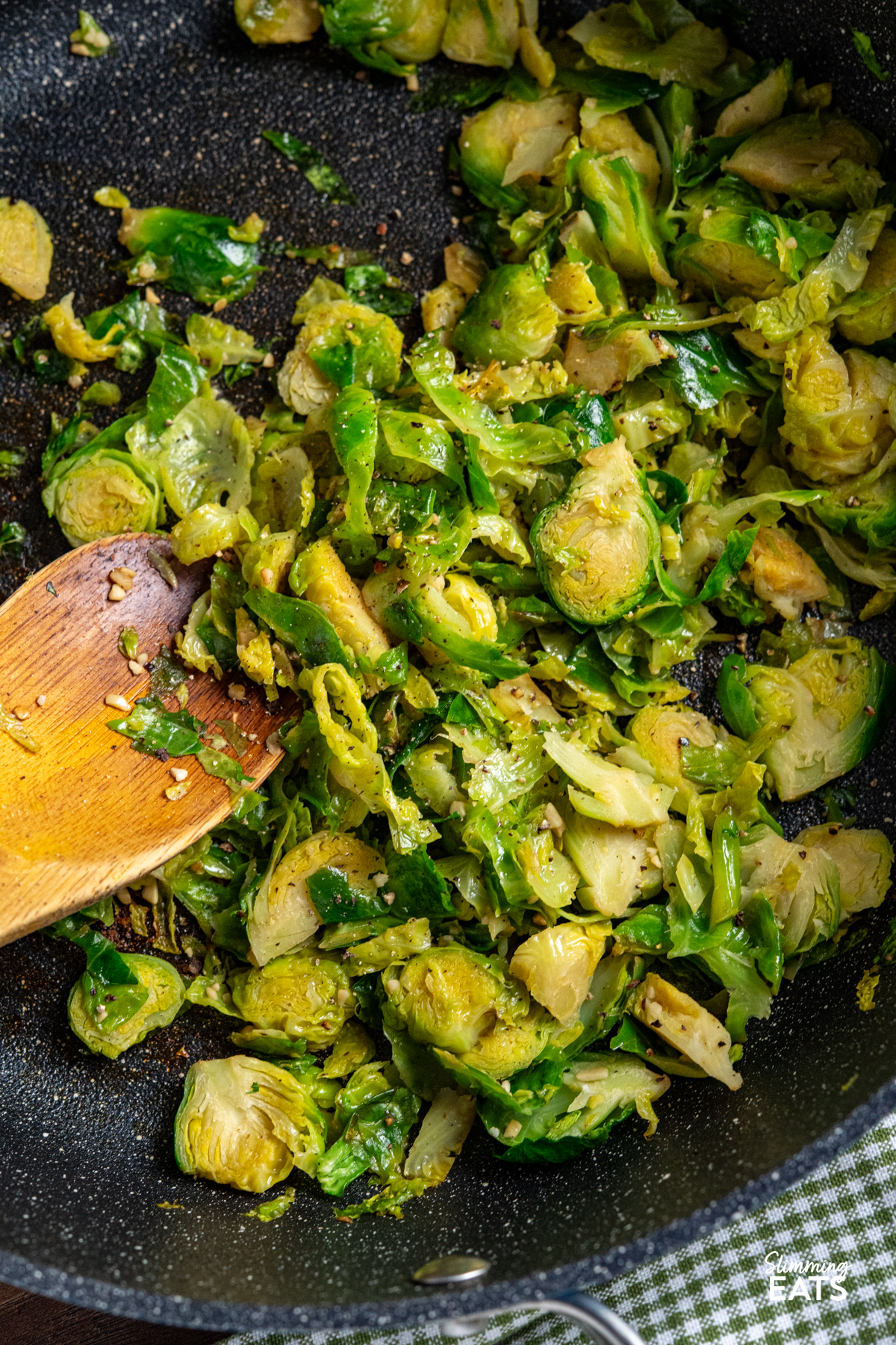 Sauteed Shredded Garlic Brussel Sprouts in non stick frying pan with wooden spoon