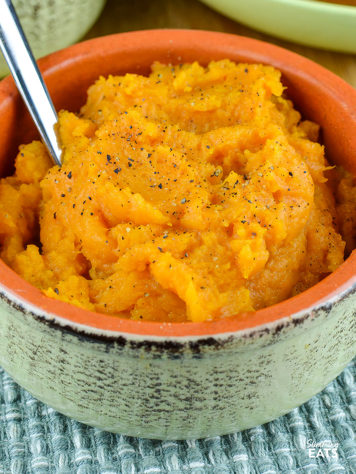 sweet potato mash in light green ceramic dish with spoon
