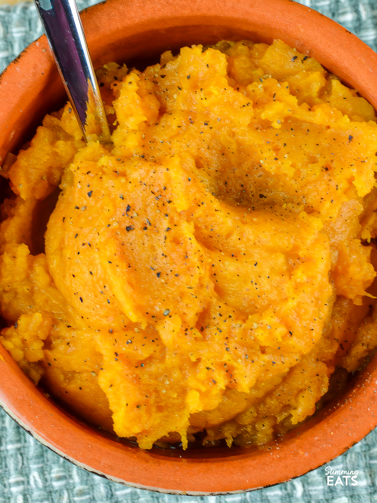 sweet potato mash in light green ceramic dish with spoon