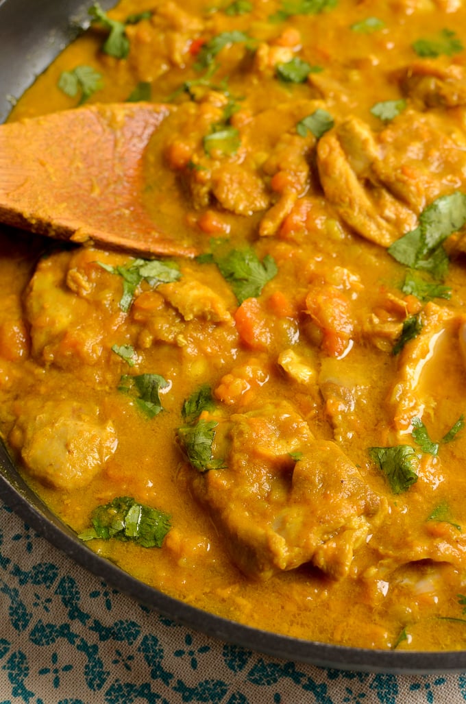 close up of Coconut Chicken and Sweet Potato Curry in skillet with wooden spoon