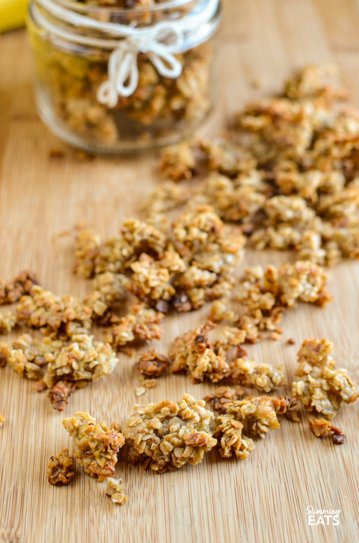 Indulge in the delightful flavours of this Banana Granola, a nutritious and tasty option that's perfect for kick-starting your day or as a scrumptious dessert. Crafted with wholesome oats, ripe bananas, and a touch of maple syrup, this granola is a fantastic low-calorie alternative that doesn't skimp on taste. Banana granola scattered on a wooden board