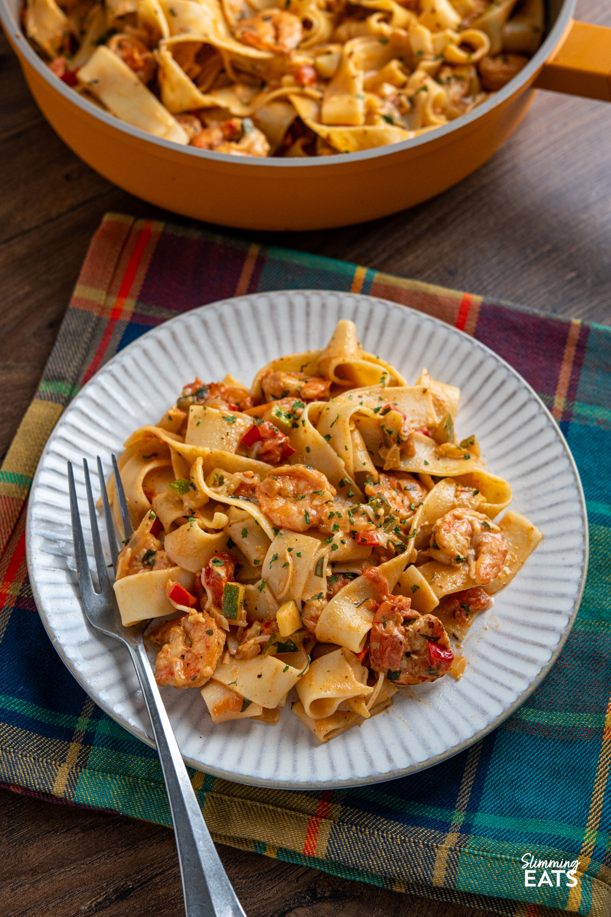 portion of Creamy Spicy Shrimp Pasta on a white plate with fork placed on left hand side of plate