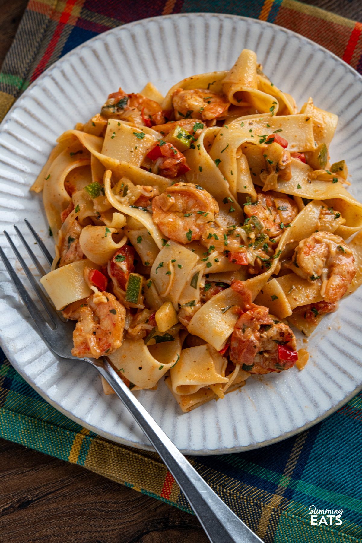 close up of portion of Creamy Spicy Shrimp Pasta on a white plate with fork placed on left hand side of plate