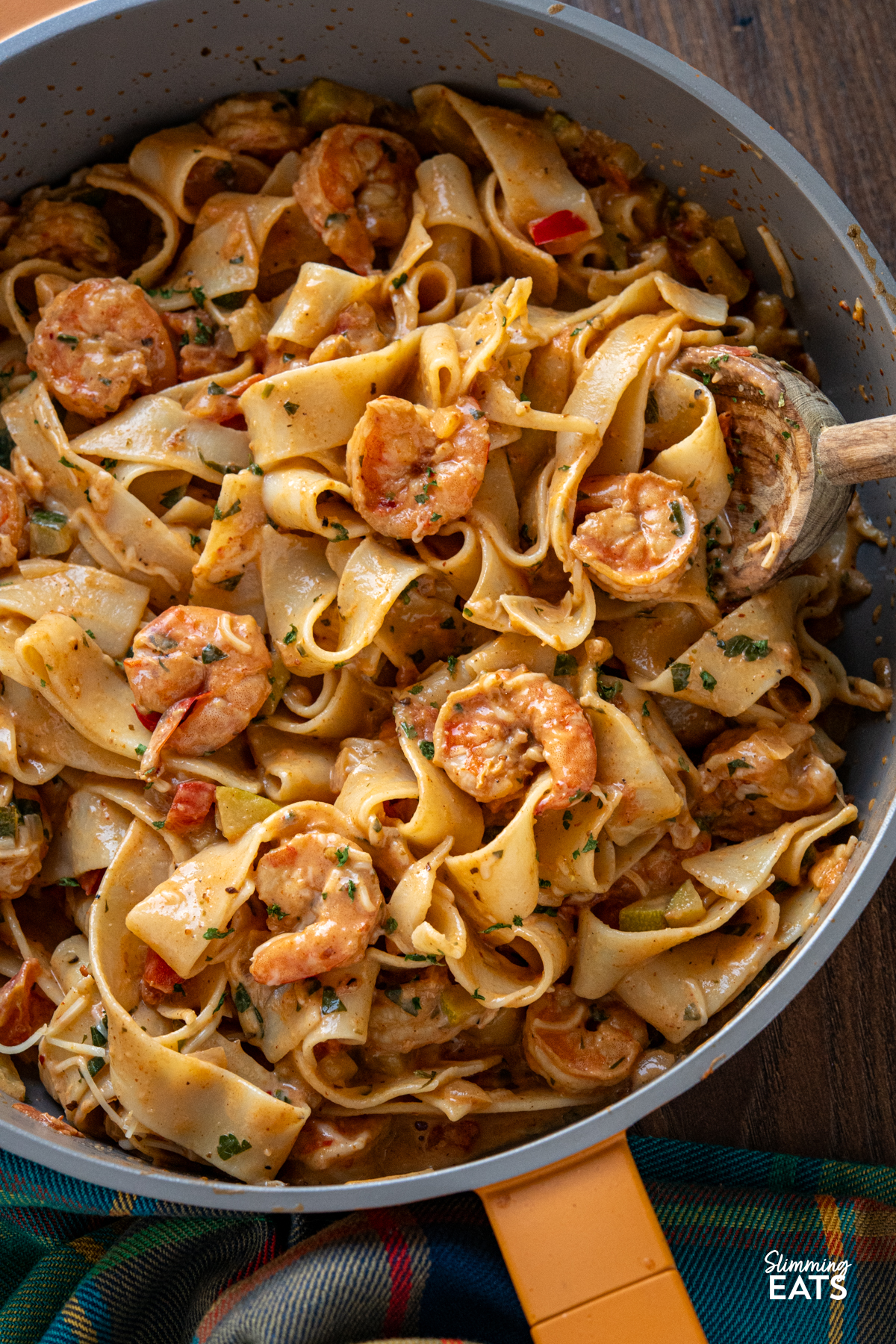 close up of Creamy Spicy Shrimp Pasta in a deep yellow non stick pan with wooden spoon 