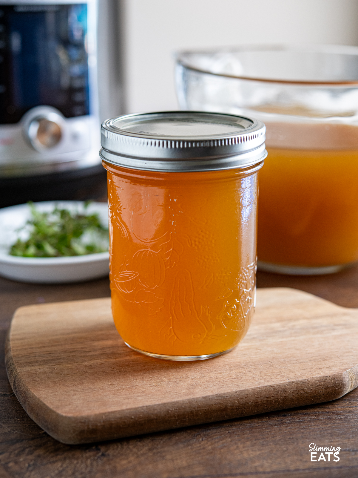 homemade chicken bone broth in a lidded mason jar in front of a pressure cooker