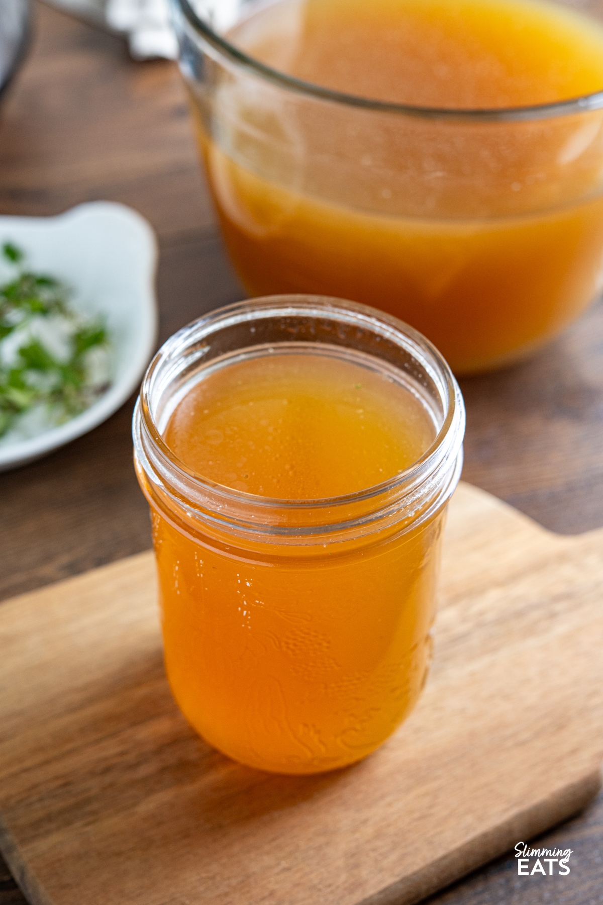 homemade chicken bone broth in a mason jar in front of a pressure cooker