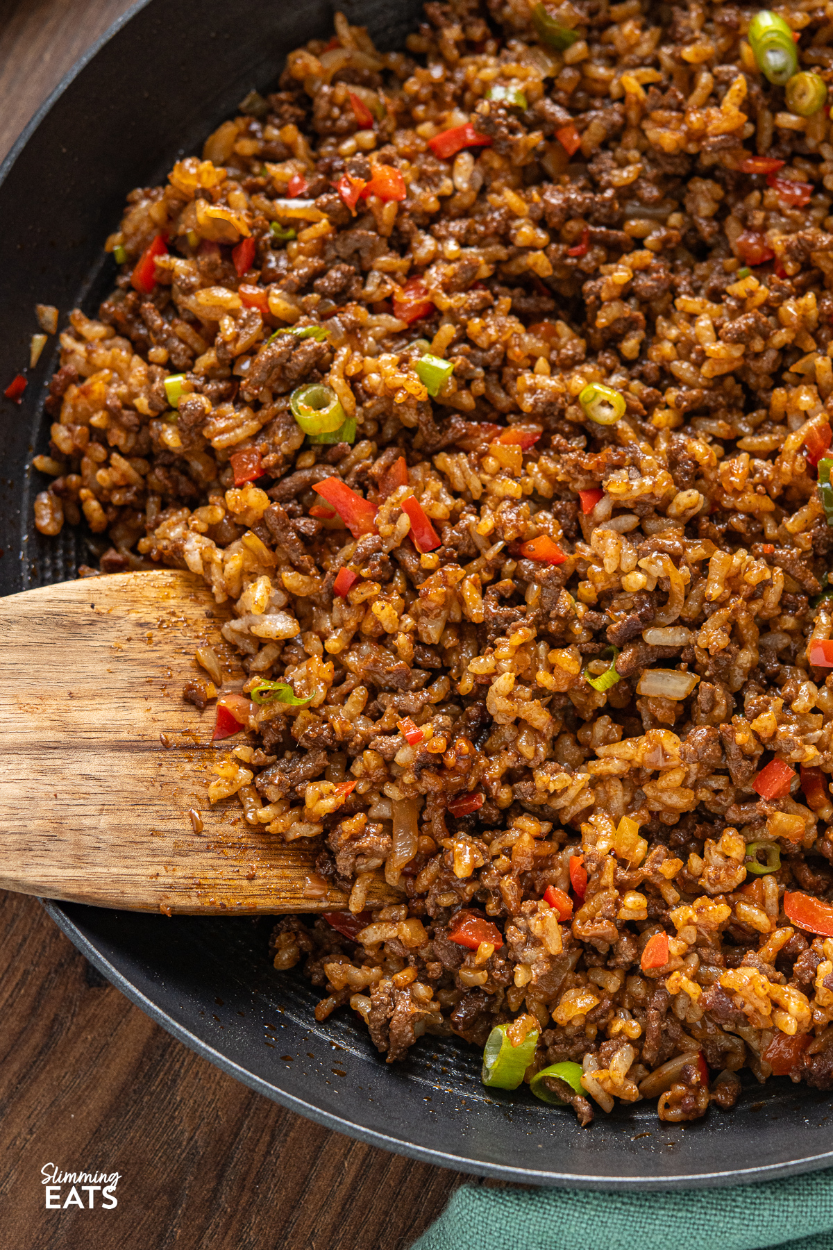 close up of Beef Nasi Goreng in a black frying pan with wooden spatula