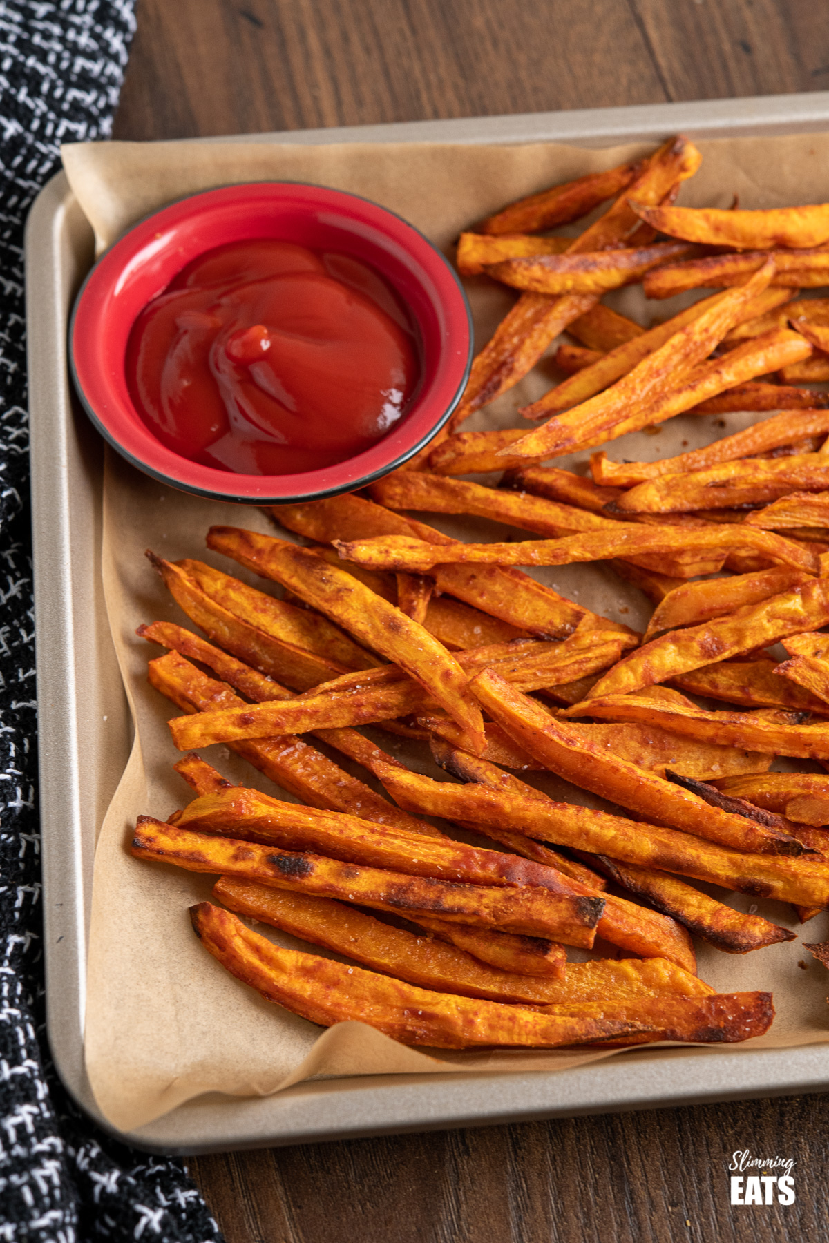 sweet potato fries on parchment lined baking tray with ketchup