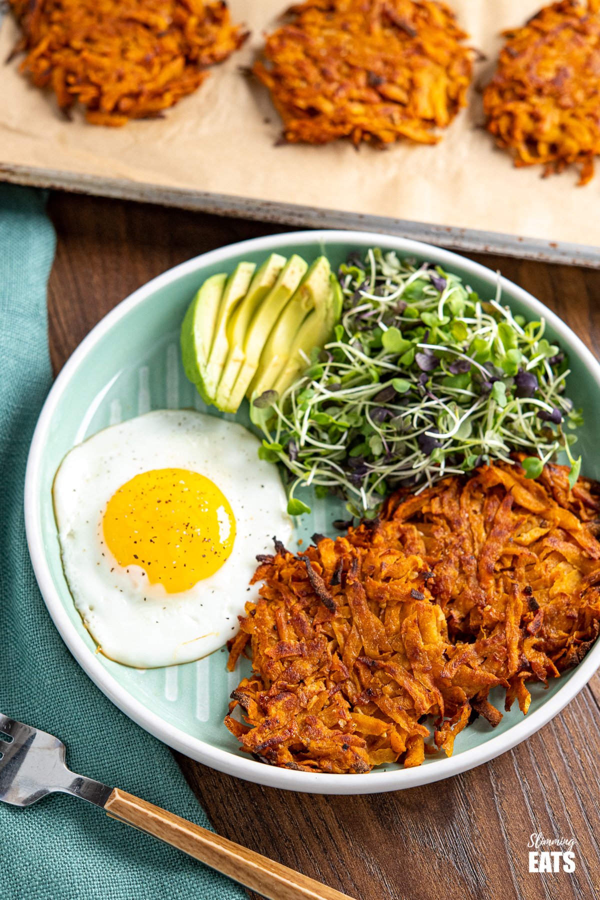Sweet Potato Hash Brown on teal coloured plate with egg, avocado and micro greens
