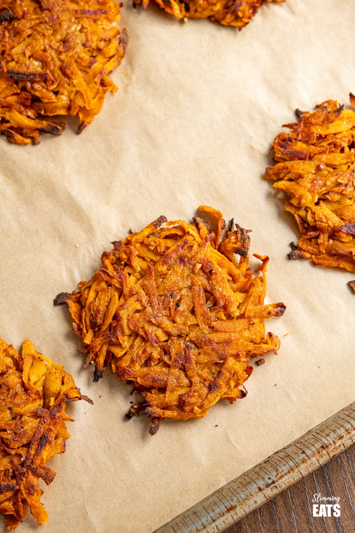 close up of oven baked sweet potato hash brown on parchment lined tray