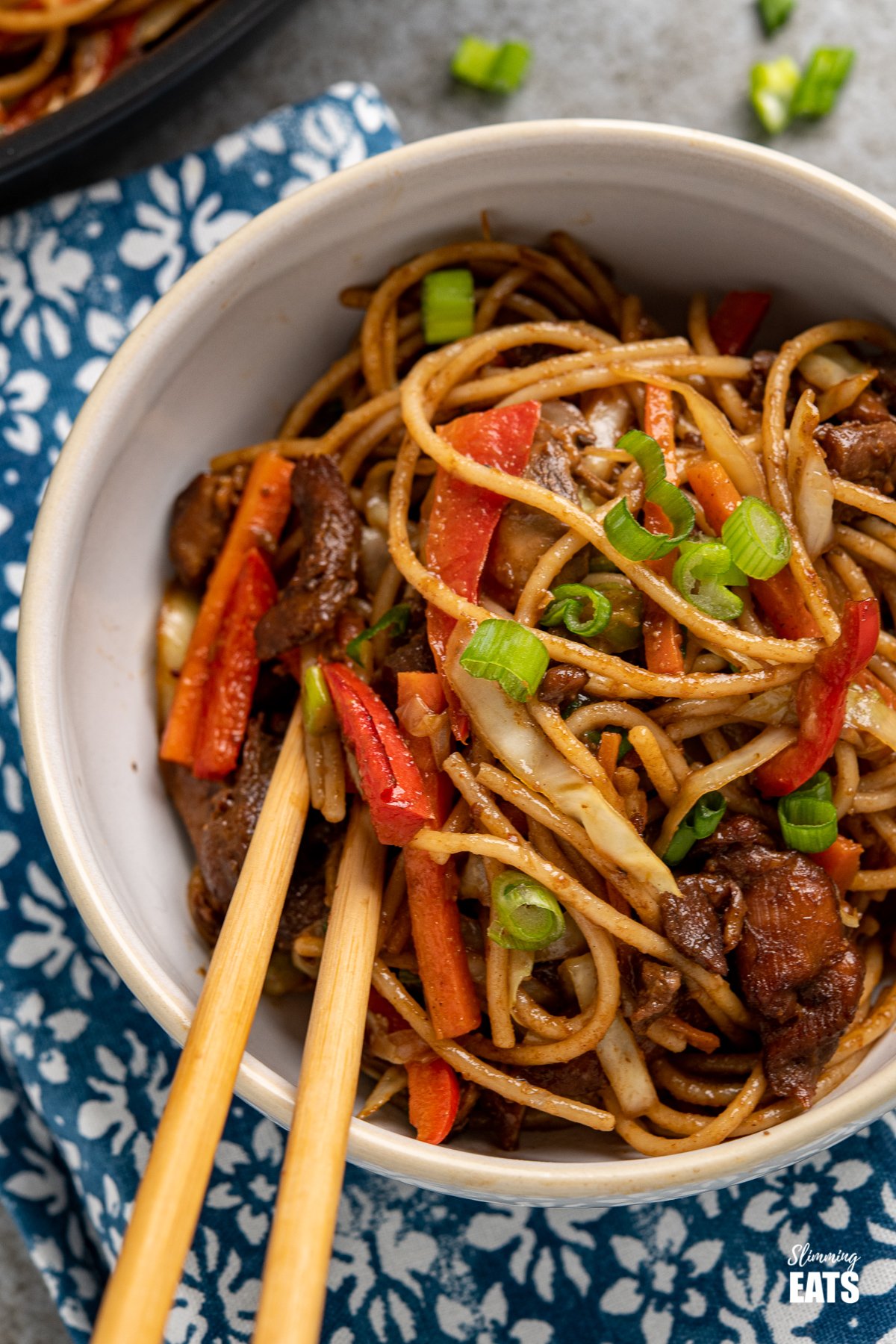 A quick to make Asian Chicken with Noodles - perfect for when you need to make dinner in a short space of time. #slimmingeats #weightwatchers #noodles #chicken close up of chicken with noodles and vegetables in a white bowl with chopsticks