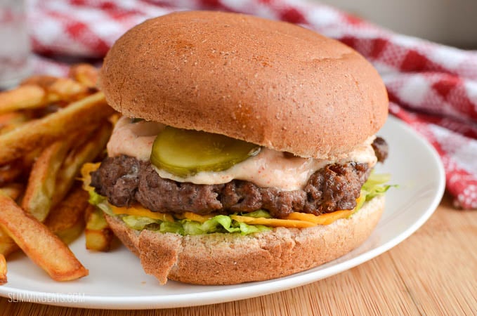 close up of lighter version of big mac and fries fakeaway on a white plate with glass of water and red and white napkin