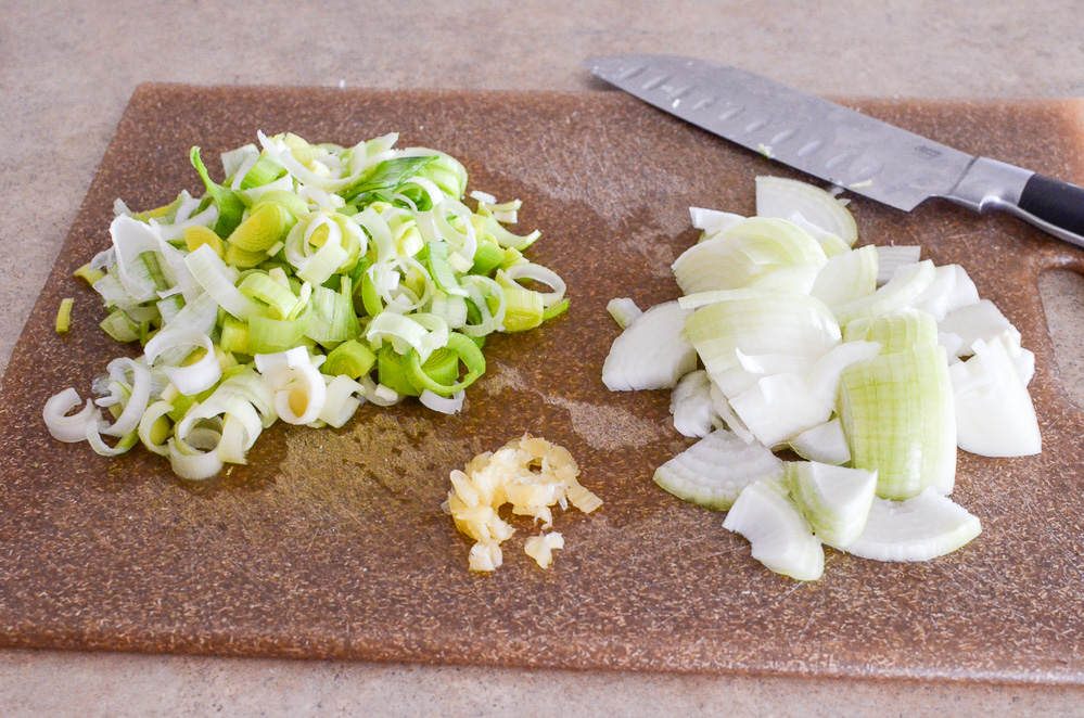 chopped onion, garlic and leeks on a chopping board