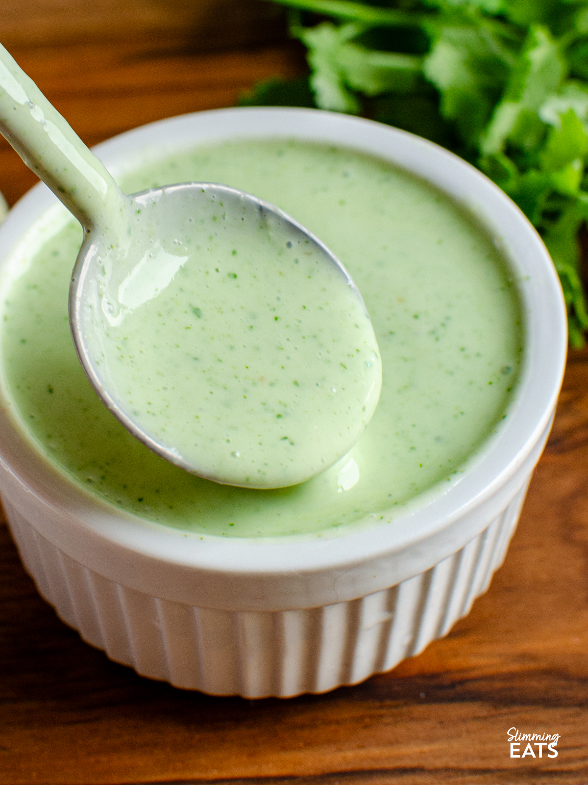 spooning some lime cilantro yoghurt dressing from a small ramekin